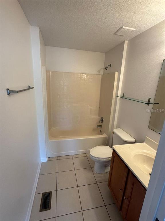 A bathroom features a beige tub-shower combination, a white toilet, and a wooden vanity cabinet — 2720 MERRIEWEATHER LANE, KISSIMMEE, FL