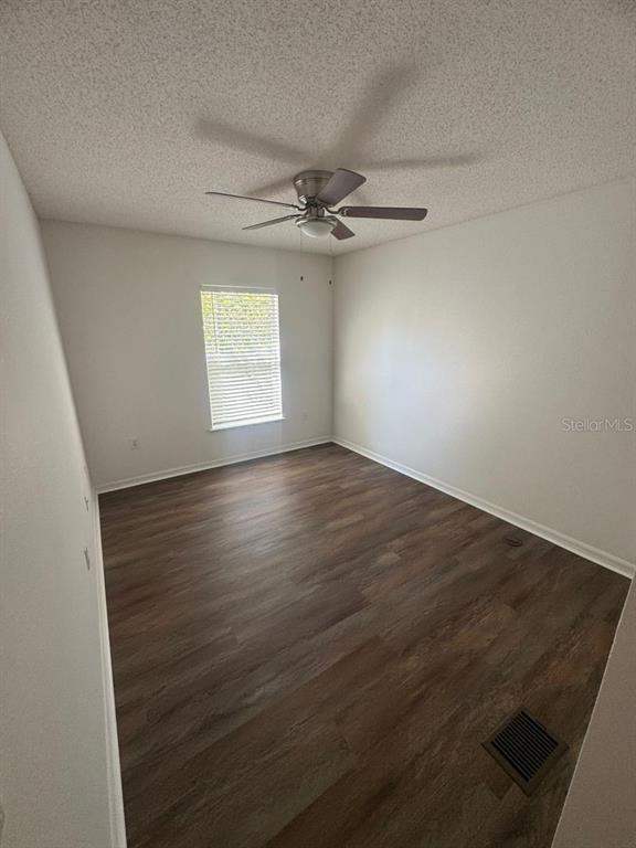 An empty bedroom features wood-look flooring, white walls, a ceiling fan, and a single window — 2720 MERRIEWEATHER LANE, KISSIMMEE, FL