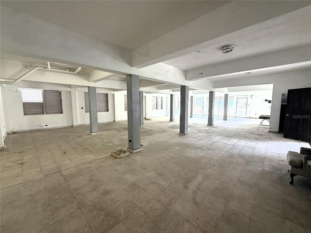 An open-plan commercial space features concrete columns, tiled flooring, and multiple windows — 12 HOSTOS CABRERA ST., SAN SEBASTIAN, PR