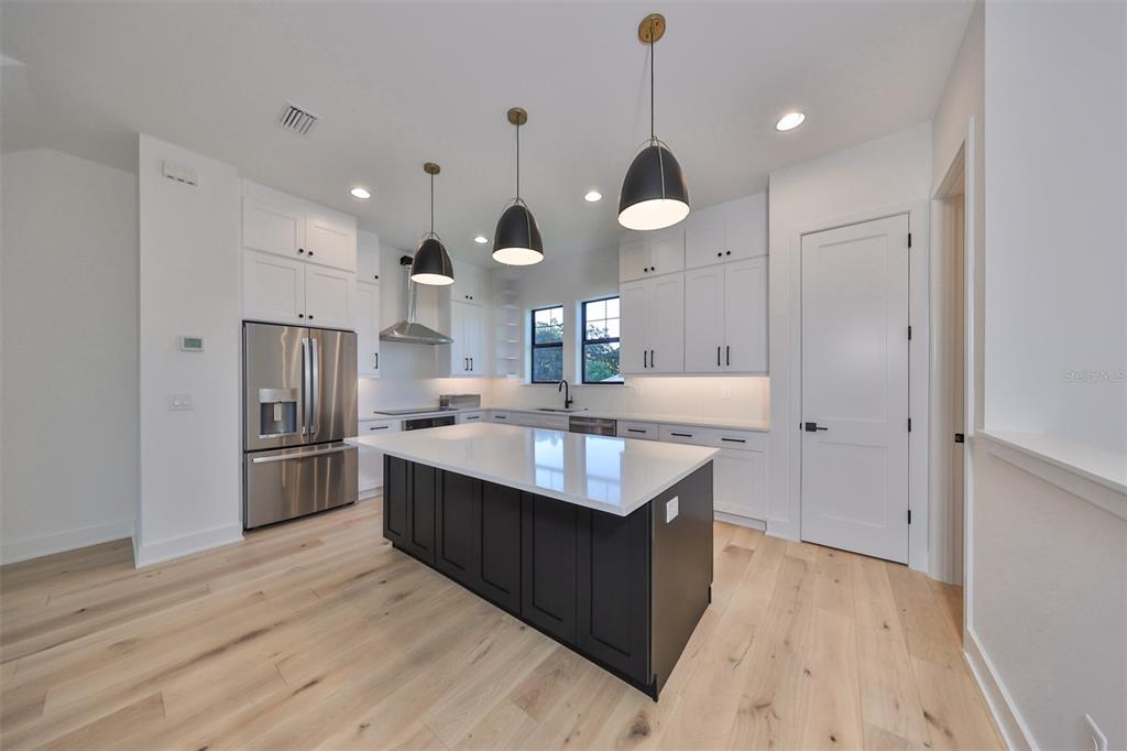 A modern kitchen features white cabinetry, a dark island, stainless steel appliances, and light flooring — 4324 W GRAY STREET UNIT 3, TAMPA, FL