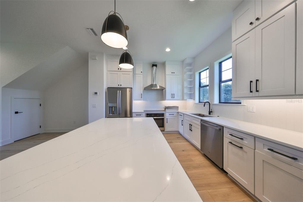 A modern kitchen features white cabinetry, a large quartz island, and stainless steel appliances — 4324 W GRAY STREET UNIT 3, TAMPA, FL