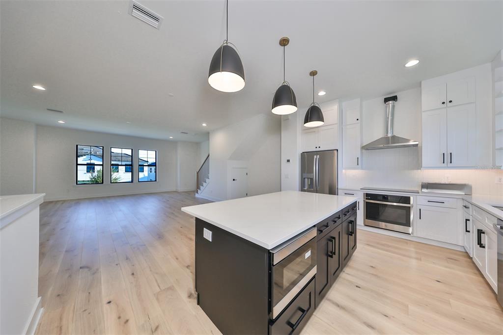 A modern kitchen with a dark island and white cabinets opens into a spacious living area — 4324 W GRAY STREET UNIT 3, TAMPA, FL