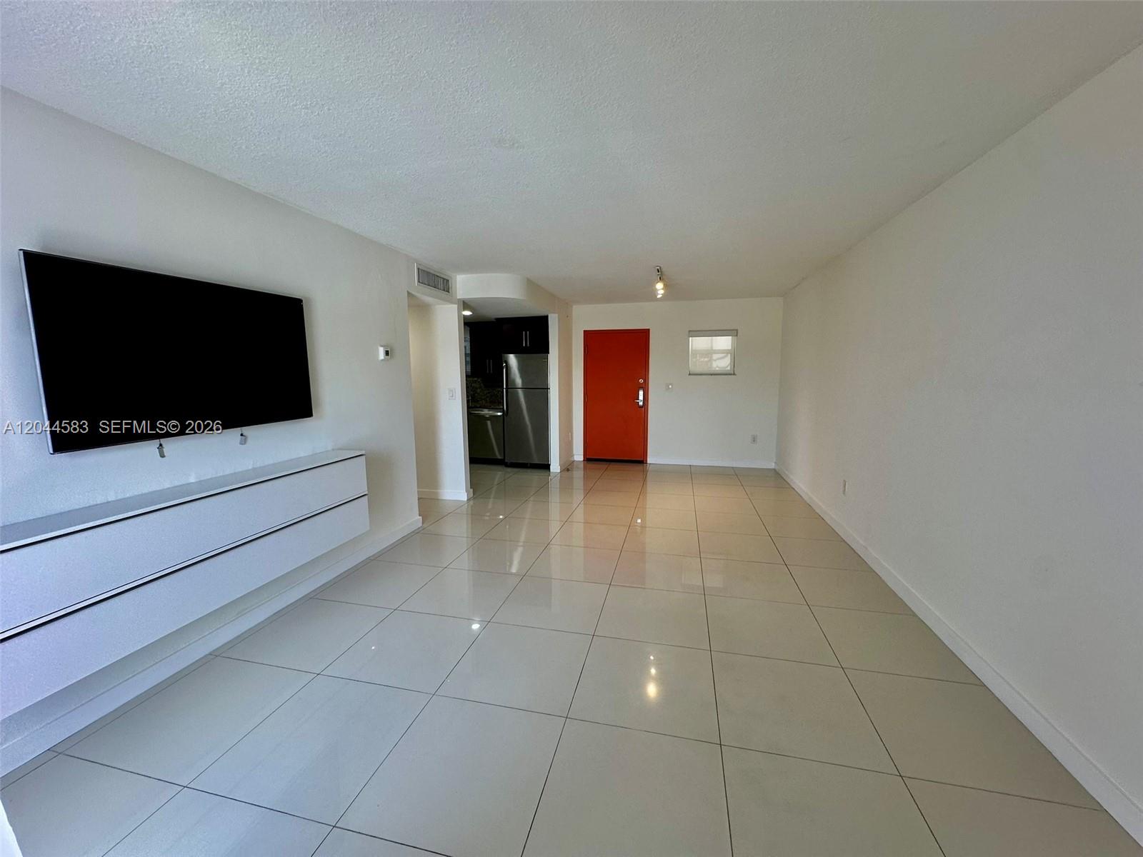 A living room features white tile flooring, a wall-mounted television, and an orange front door — 411 SW 37th Ave # 3D, Miami FL 33135, MIAMI, FL
