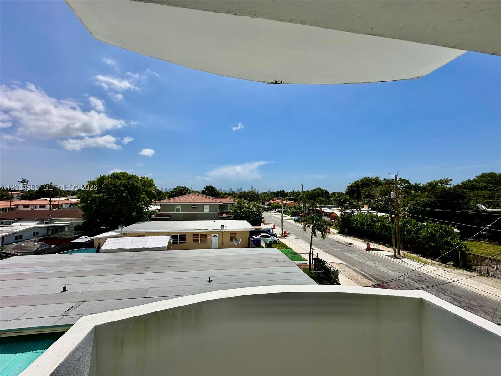 An elevated view from a balcony overlooks a residential street, rooftops, and distant city skyline — 411 SW 37th Ave # 3D, Miami FL 33135, MIAMI, FL