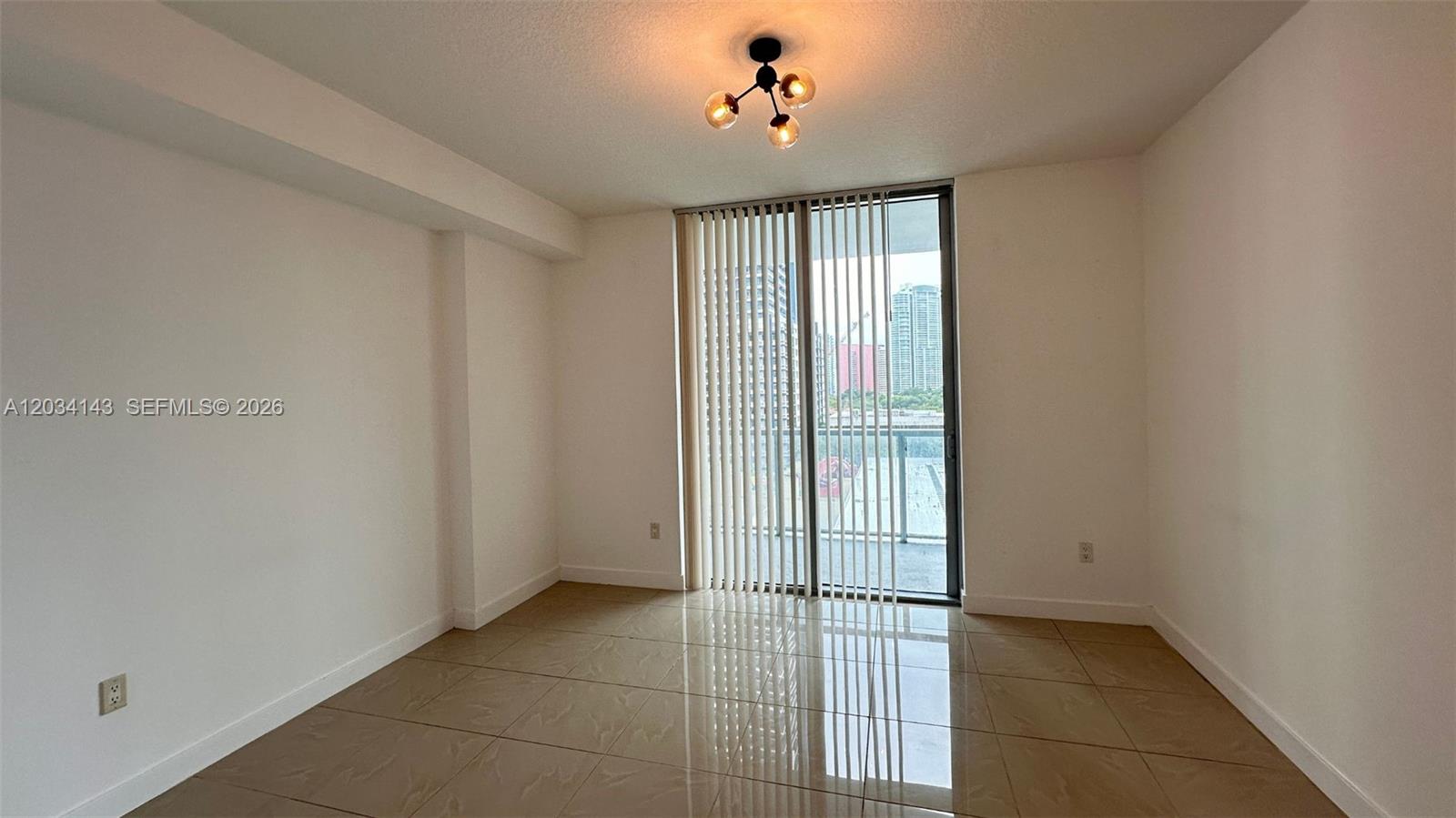 An empty room features beige tile flooring, white walls, and a sliding glass door — 79 SW 12th St, Miami FL 33130, MIAMI, FL