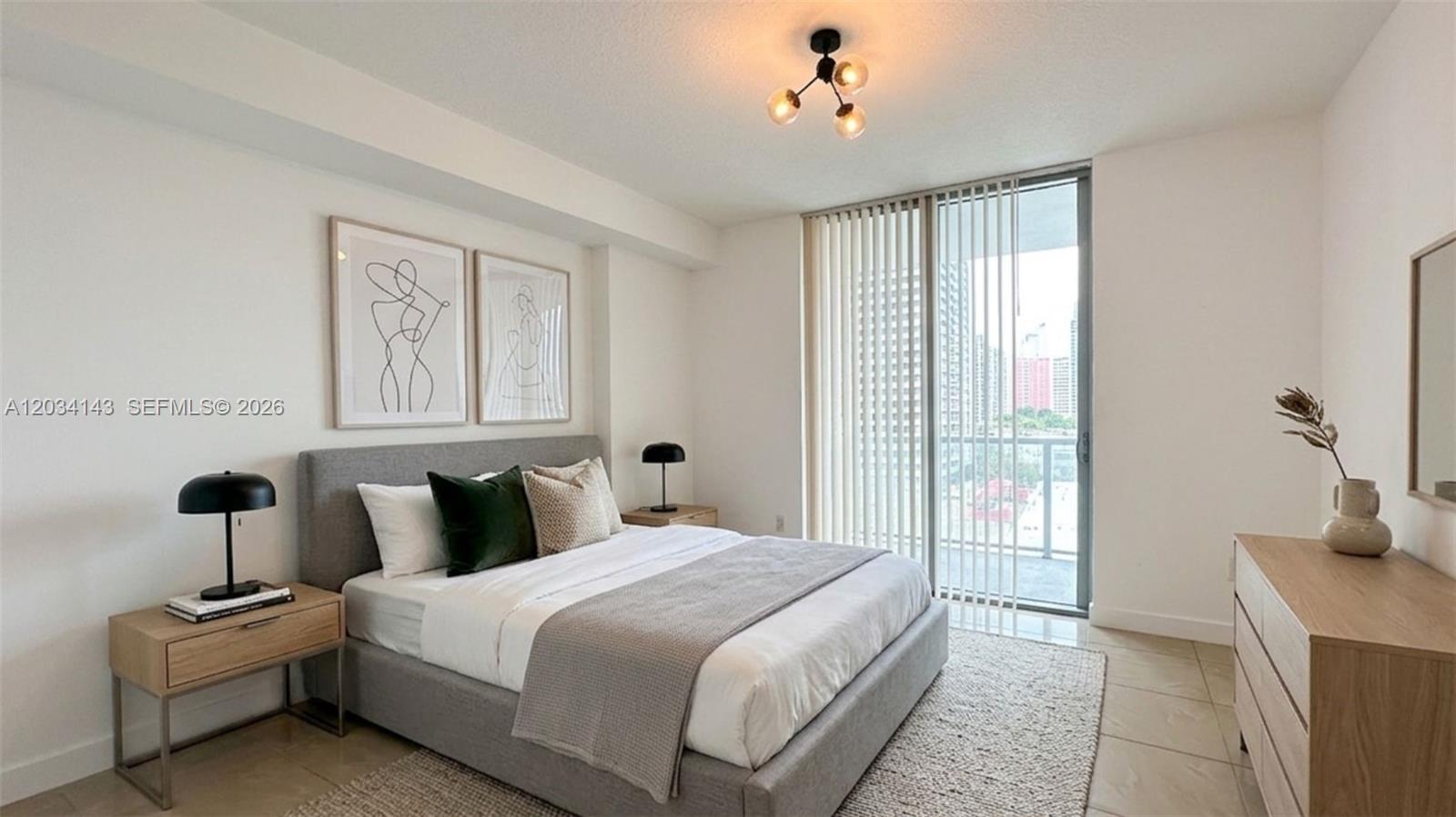 A modern bedroom features a gray upholstered bed, light wood furniture, and a balcony door — 79 SW 12th St, Miami FL 33130, MIAMI, FL