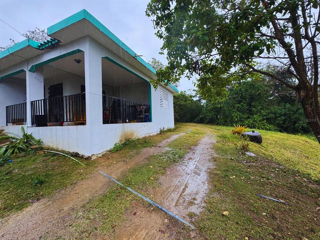 A white house with a teal roof and a covered porch sits on a grassy lot — Calle #10 COMM MONTE SANTO P-2, VIEQUES, PR