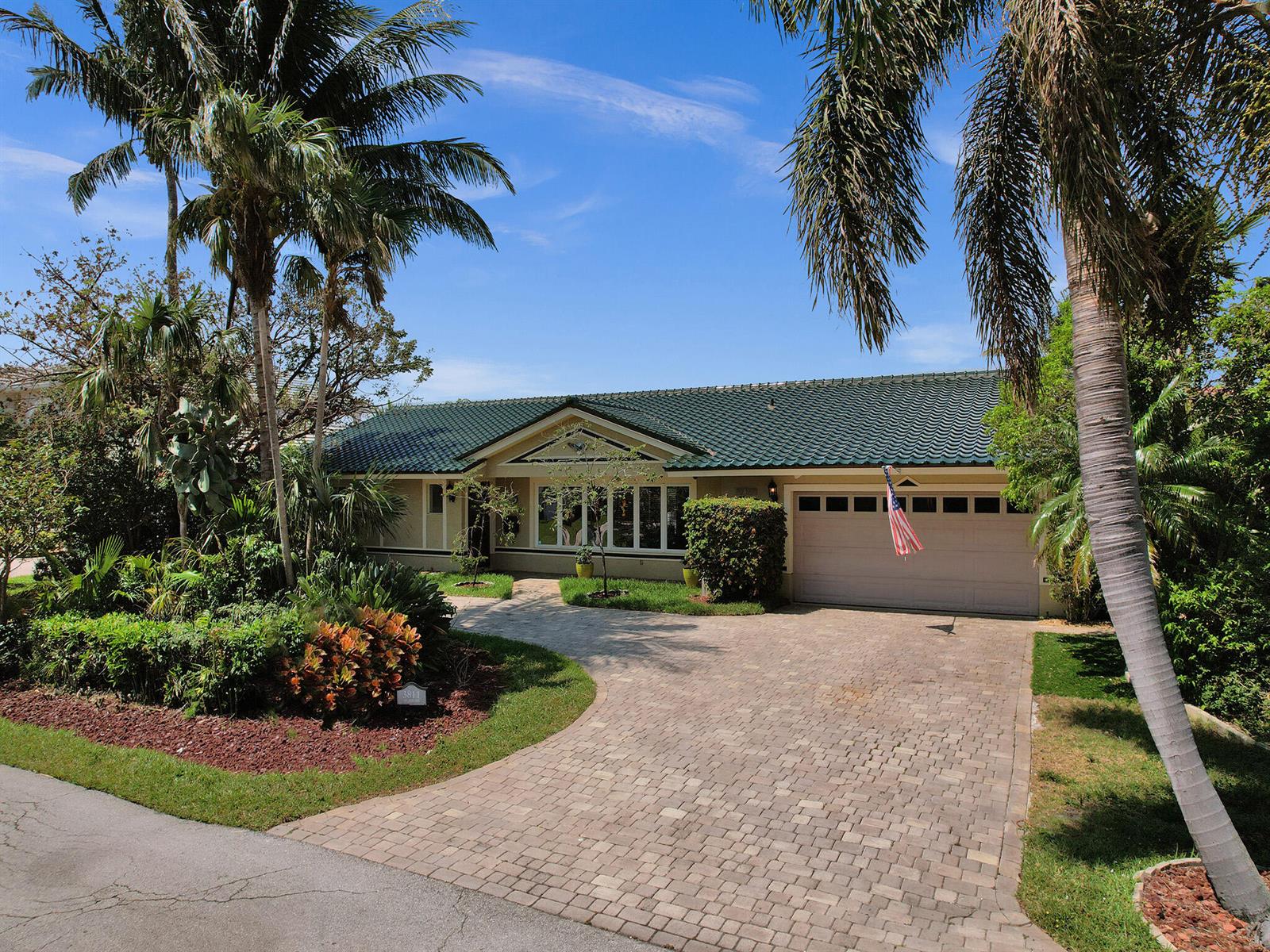 A single-story house with a green tile roof and a paved driveway surrounded by palms — 3811 NE 26th Avenue, Lighthouse Point FL 33064, LIGHTHOUSE POINT, FL