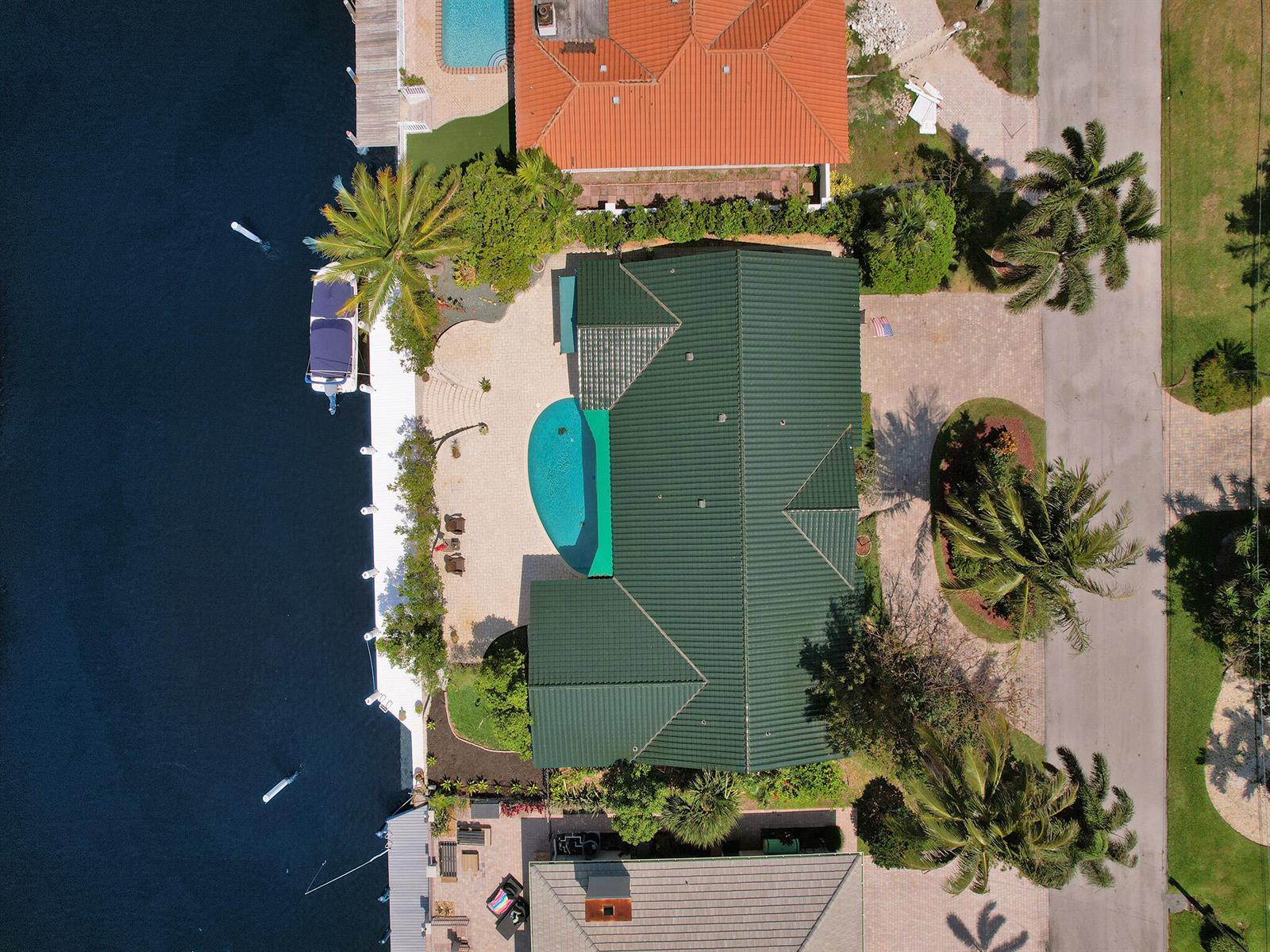 An aerial view shows a waterfront house with a green roof, pool, and boat dock — 3811 NE 26th Avenue, Lighthouse Point FL 33064, LIGHTHOUSE POINT, FL