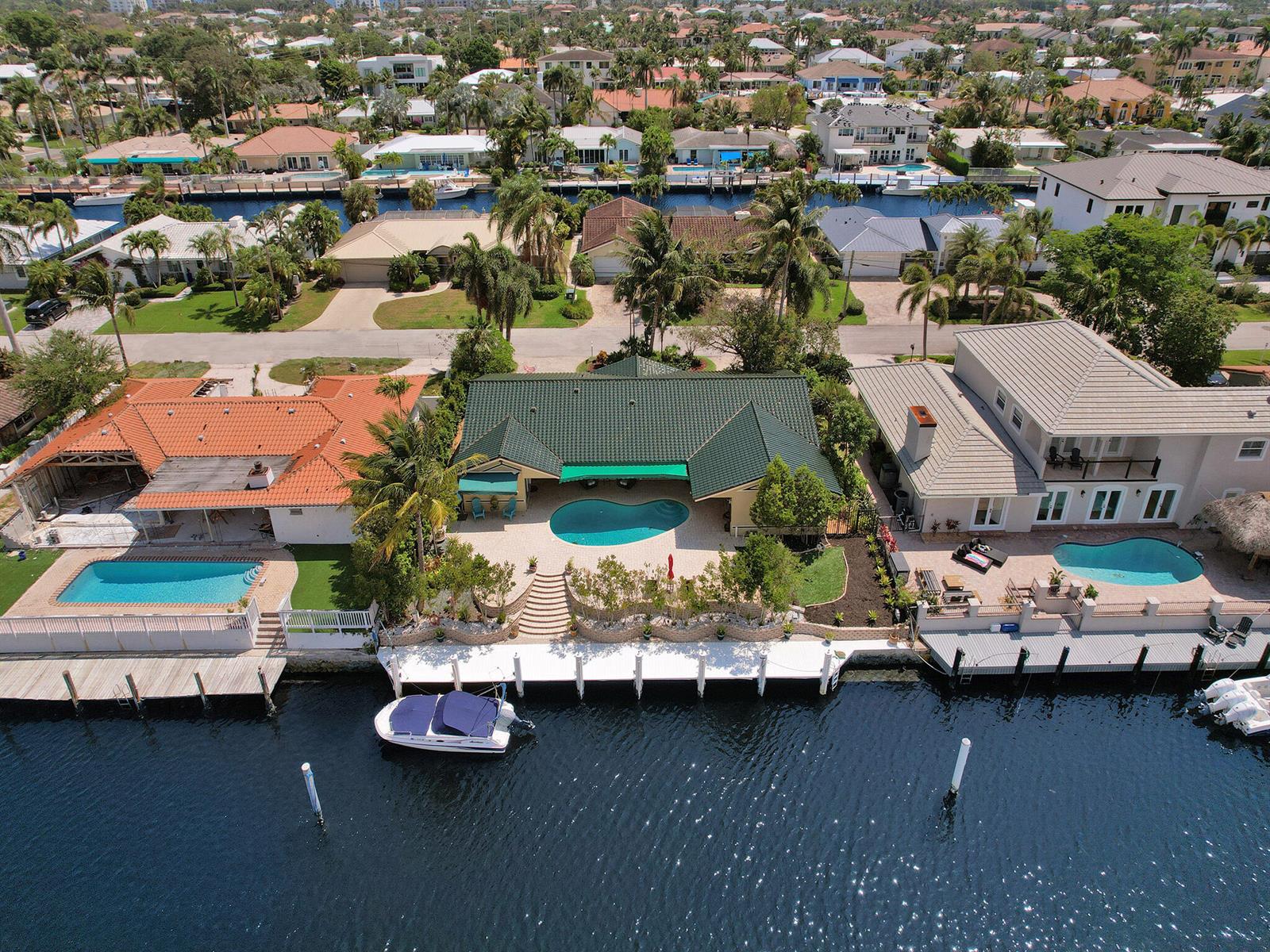 An aerial view shows a waterfront house with a green roof, pool, and private dock — 3811 NE 26th Avenue, Lighthouse Point FL 33064, LIGHTHOUSE POINT, FL