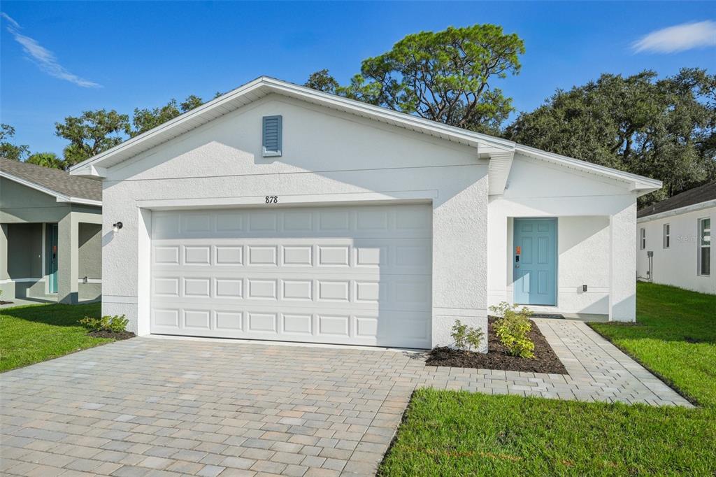 A white single-story house with a two-car garage and a light blue front door — 1006 AMBLESIDE DRIVE, HAINES CITY, FL