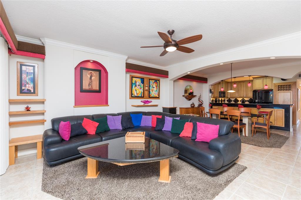 A living room with a large black sectional sofa, coffee table, and open kitchen area — 80 SURFVIEW DRIVE UNIT 103, PALM COAST, FL