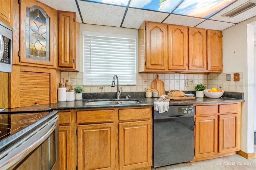 This kitchen features oak cabinets, black countertops, a drop-in sink, and a drop ceiling — 100 SILVER BEACH AVENUE UNIT 816, DAYTONA BEACH, FL