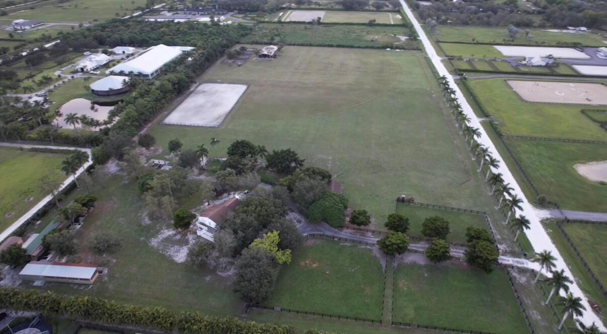 Aerial view of a large equestrian property featuring pastures, riding arenas, and a residential house — 16098 Deer Path Lane, Wellington FL 33470, WELLINGTON, FL