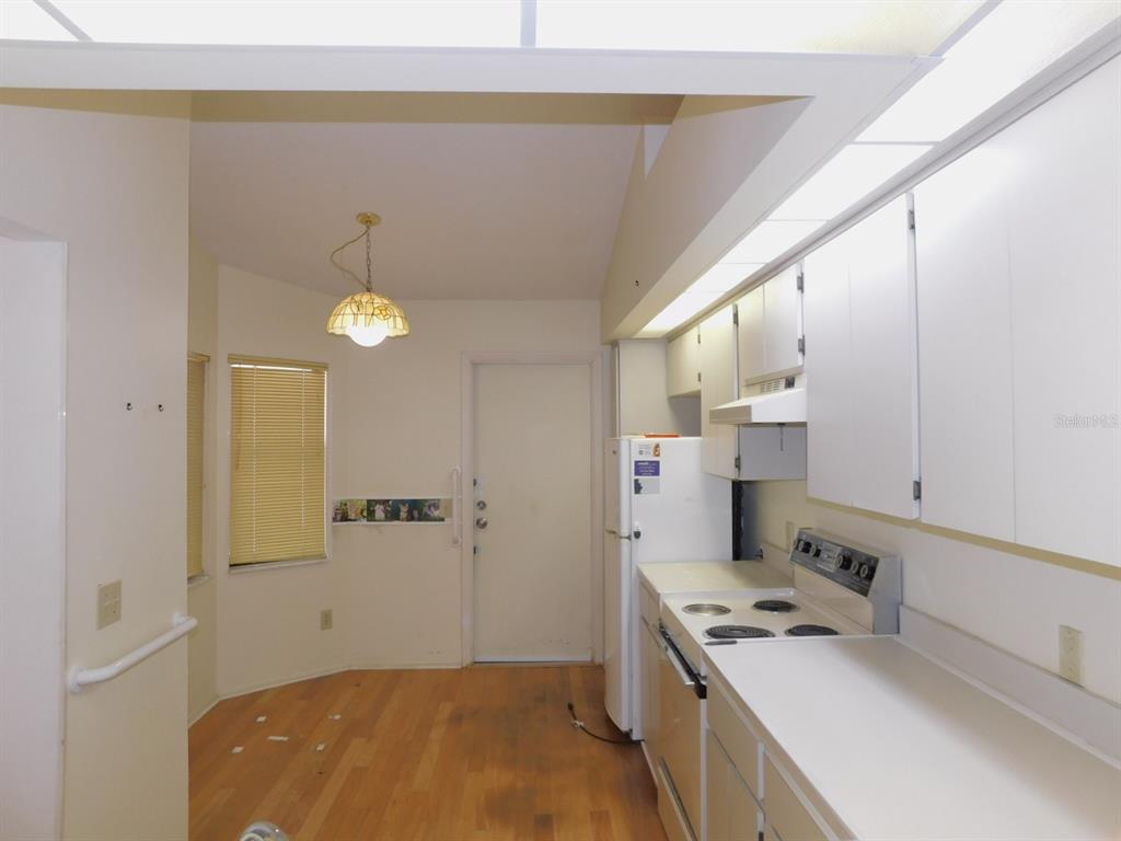 A kitchen with white cabinets, a white stove, a refrigerator, and light wood flooring — 2496 ALHAMBRA COURT, CLEARWATER, FL