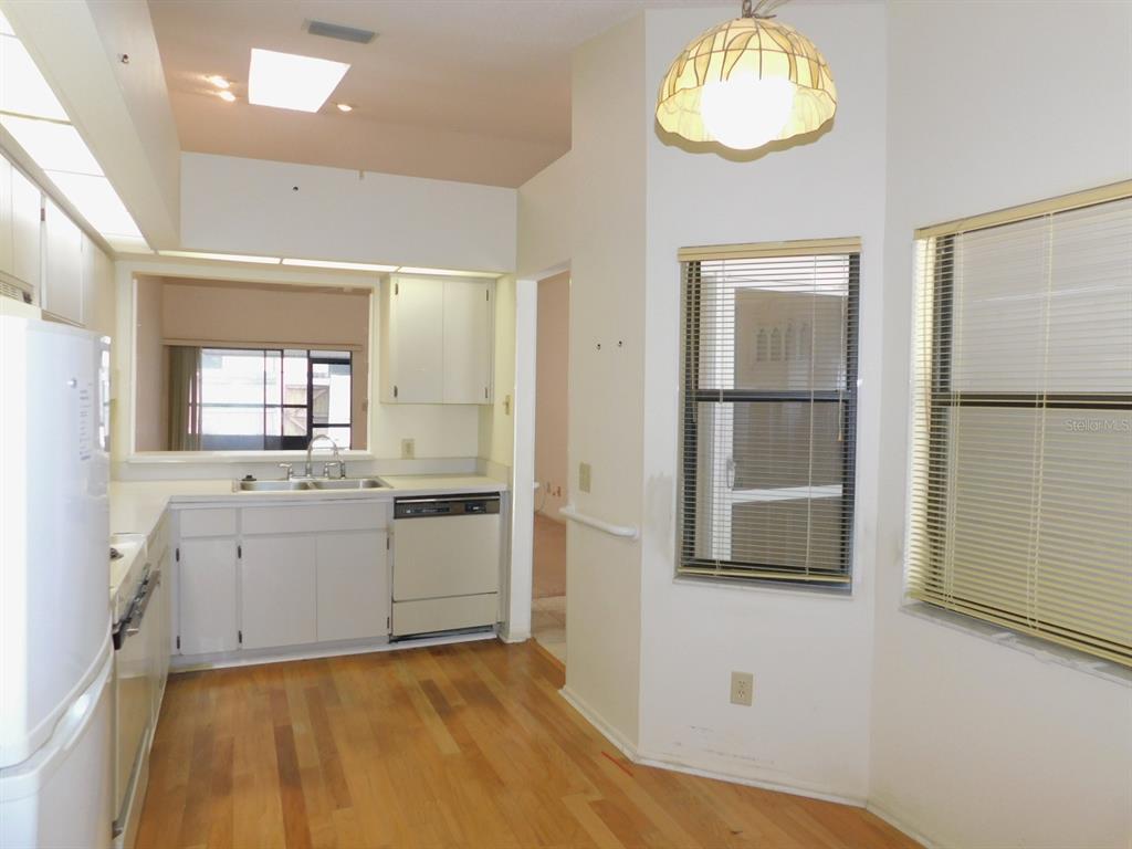 A kitchen with white cabinets, light wood flooring, a dishwasher, and a breakfast nook area — 2496 ALHAMBRA COURT, CLEARWATER, FL