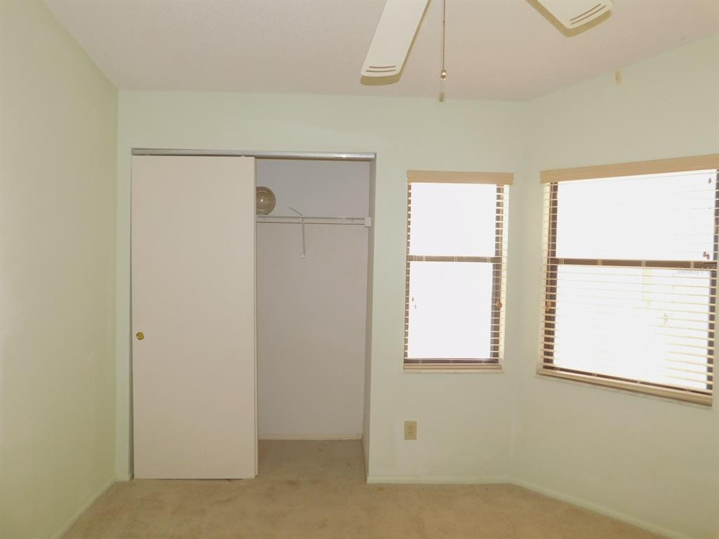 A bedroom with light green walls, beige carpet, a sliding closet door, and two windows — 2496 ALHAMBRA COURT, CLEARWATER, FL