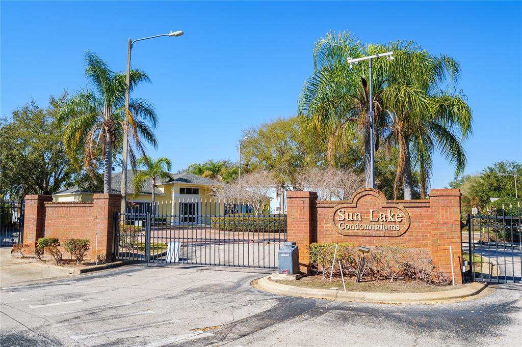 A brick entrance sign for Sun Lake Condominiums stands before a gated community driveway — 3125 SUN LAKE COURT UNIT B, KISSIMMEE, FL