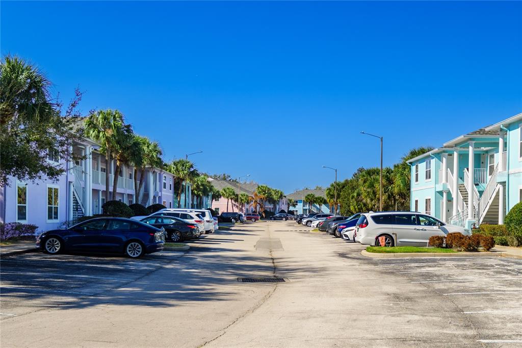 A parking lot sits between two rows of multi-story apartment buildings with palm trees — 3125 SUN LAKE COURT UNIT B, KISSIMMEE, FL