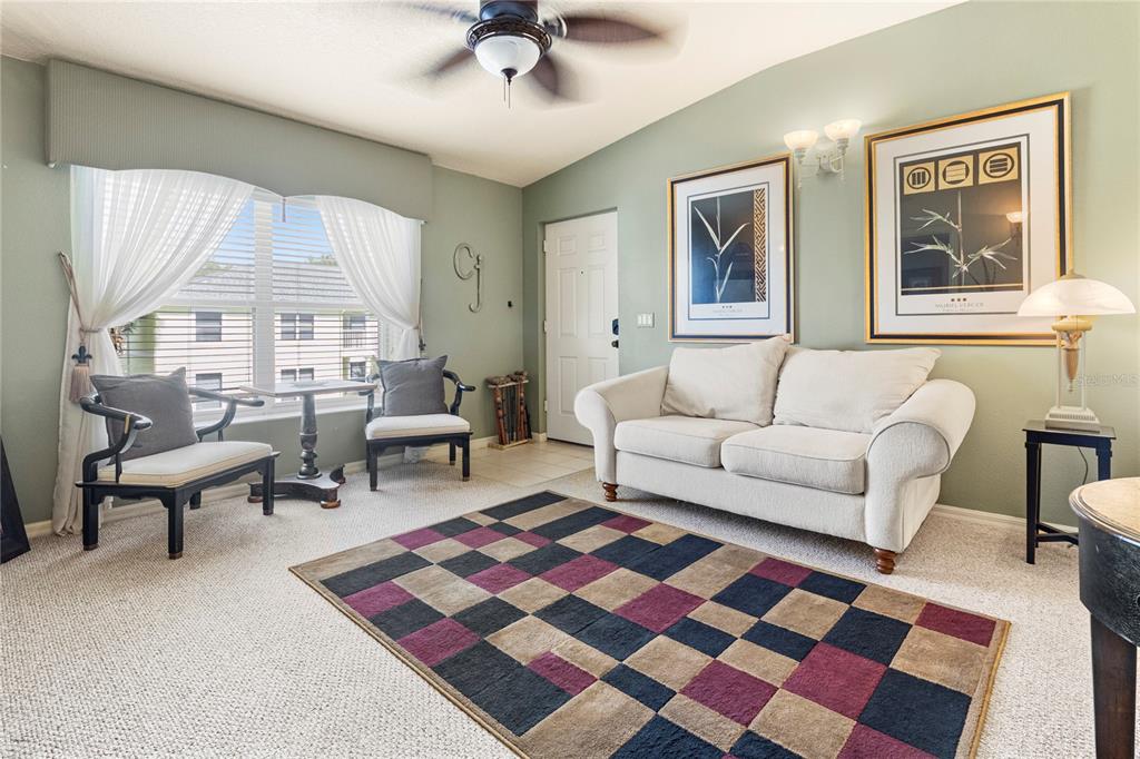 A living room features a white sofa, two accent chairs, a patterned rug, and artwork — 3125 SUN LAKE COURT UNIT B, KISSIMMEE, FL