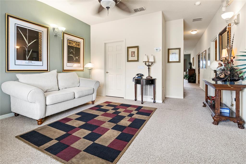 A living room features a white sofa, a checkered rug, and a hallway leading away — 3125 SUN LAKE COURT UNIT B, KISSIMMEE, FL