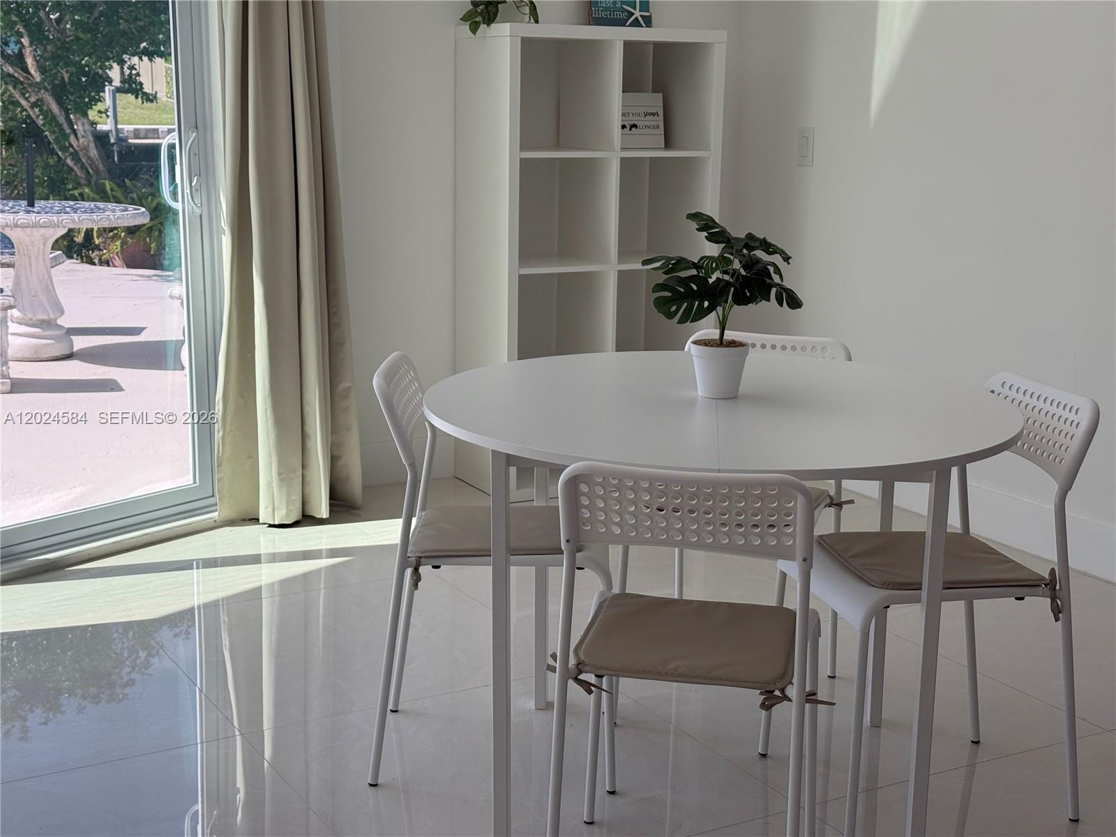 A white dining set with four chairs sits in a bright room with tiled floors — 411 SE 6th Ave, Pompano Beach FL 33060, POMPANO BEACH, FL