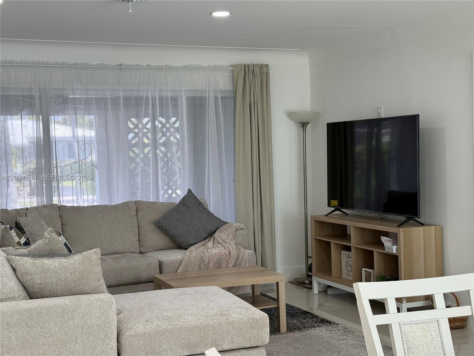 A living room features a beige sectional sofa, a wooden coffee table, and a television stand — 411 SE 6th Ave, Pompano Beach FL 33060, POMPANO BEACH, FL