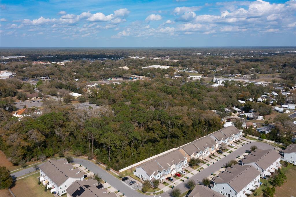An aerial view shows a wooded lot adjacent to a residential townhouse community — E. 10th Street COUNTRYMEN COURT., APOPKA, FL