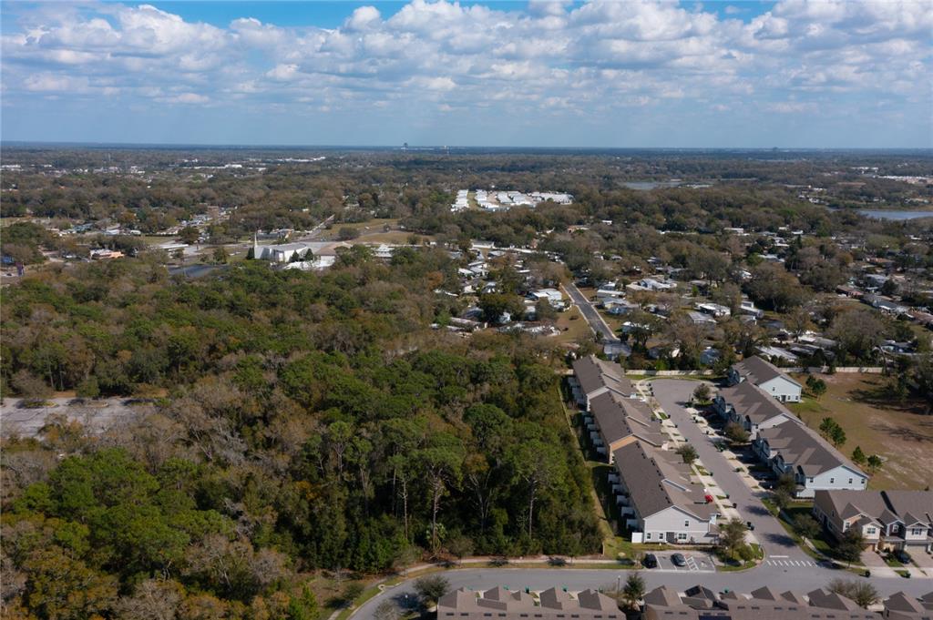 An aerial view shows a residential neighborhood with townhomes adjacent to a large wooded area — E. 10th Street COUNTRYMEN COURT., APOPKA, FL