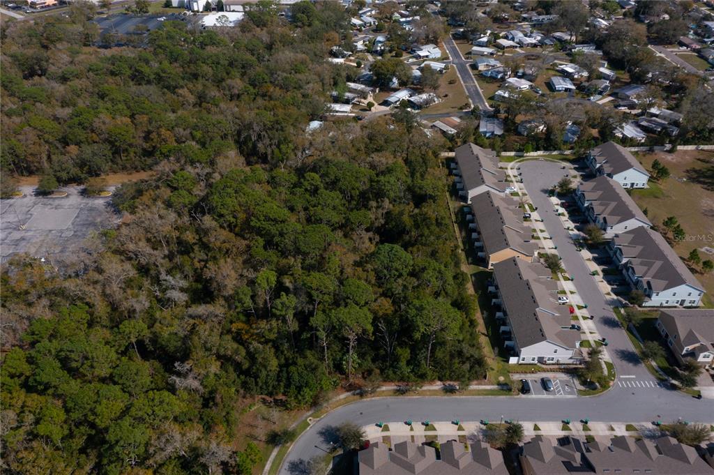 An aerial view shows a wooded lot adjacent to a residential townhouse complex and parking area — E. 10th Street COUNTRYMEN COURT., APOPKA, FL