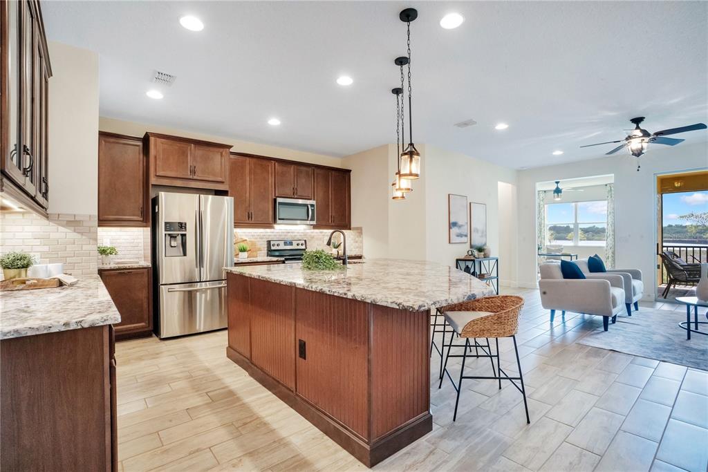 A kitchen with wood cabinets and a granite island opens to a living area — 9009 PALM KEY AVENUE, OLDSMAR, FL