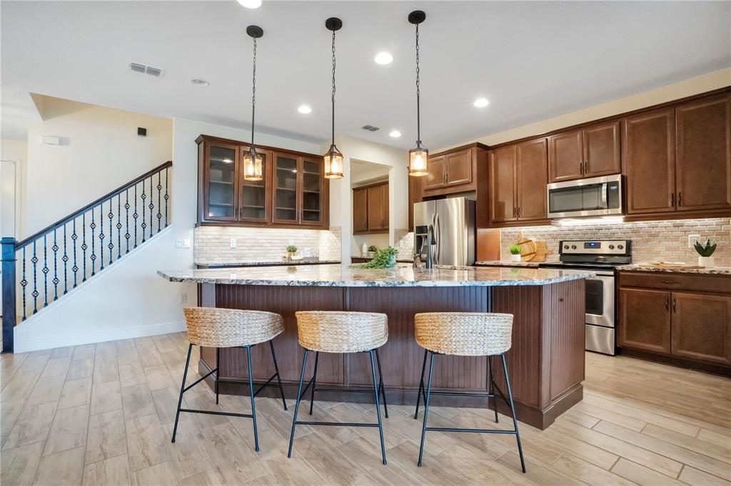 A kitchen features dark wood cabinets, granite countertops, a large island, and three woven stools — 9009 PALM KEY AVENUE, OLDSMAR, FL