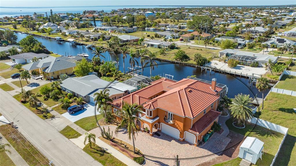 An aerial view of a two-story orange house with a tiled roof near a canal — 108 ROSELLE COURT, PORT CHARLOTTE, FL