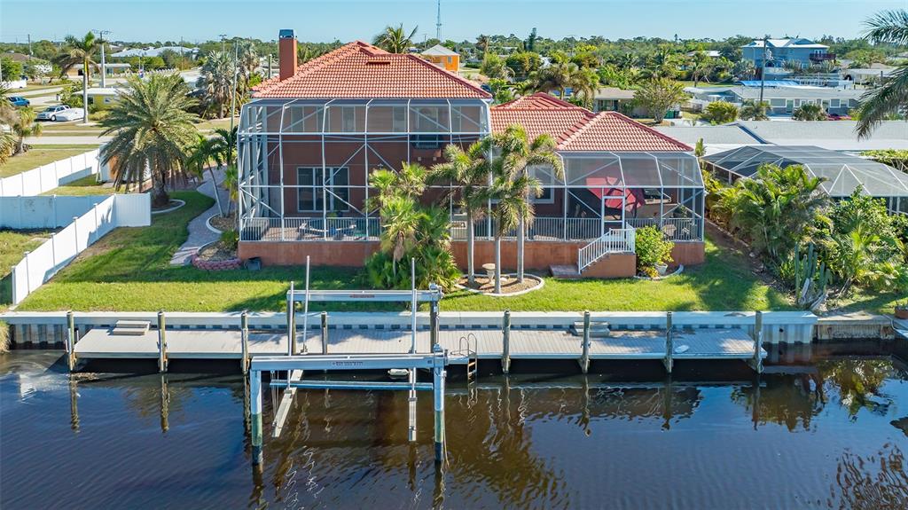 An aerial view of a waterfront house with a screened-in lanai and a boat lift — 108 ROSELLE COURT, PORT CHARLOTTE, FL