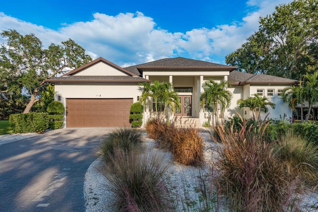 A single-story house with a brown garage, palm trees, and a paved driveway — 7811 BAY DRIVE UNIT A, TAMPA, FL