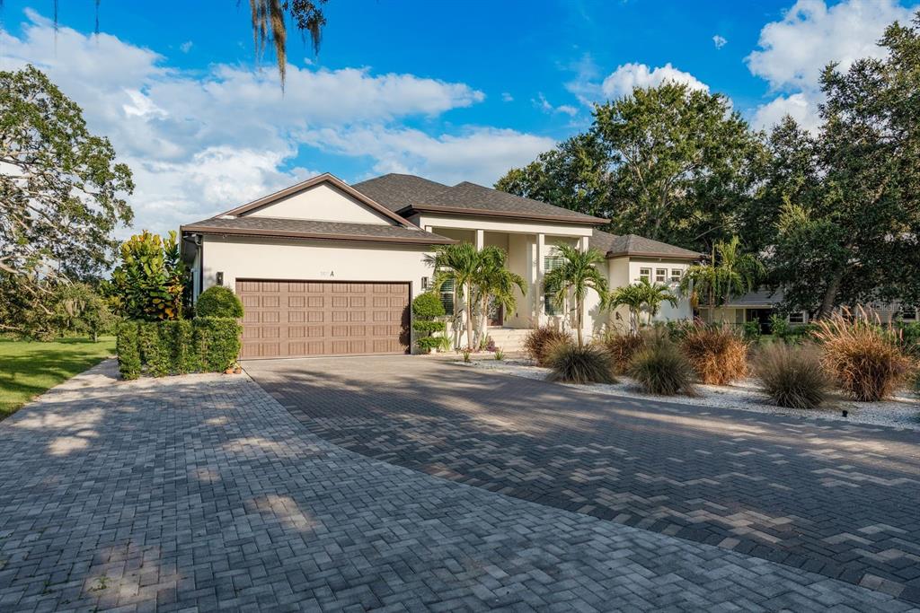 A single-story house with a brown garage door and a paved driveway under a blue sky — 7811 BAY DRIVE UNIT A, TAMPA, FL