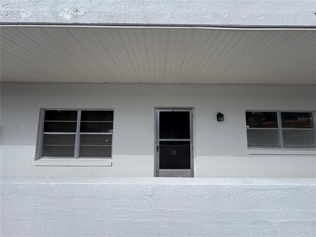 A white exterior wall features a central door numbered 111 flanked by two windows — 100 EL CAMINO DRIVE UNIT 111, WINTER HAVEN, FL