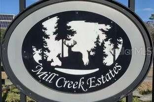 An oval sign for Mill Creek Estates features a black silhouette of deer and trees — 13645 NW 222ND LANE, ALACHUA, FL