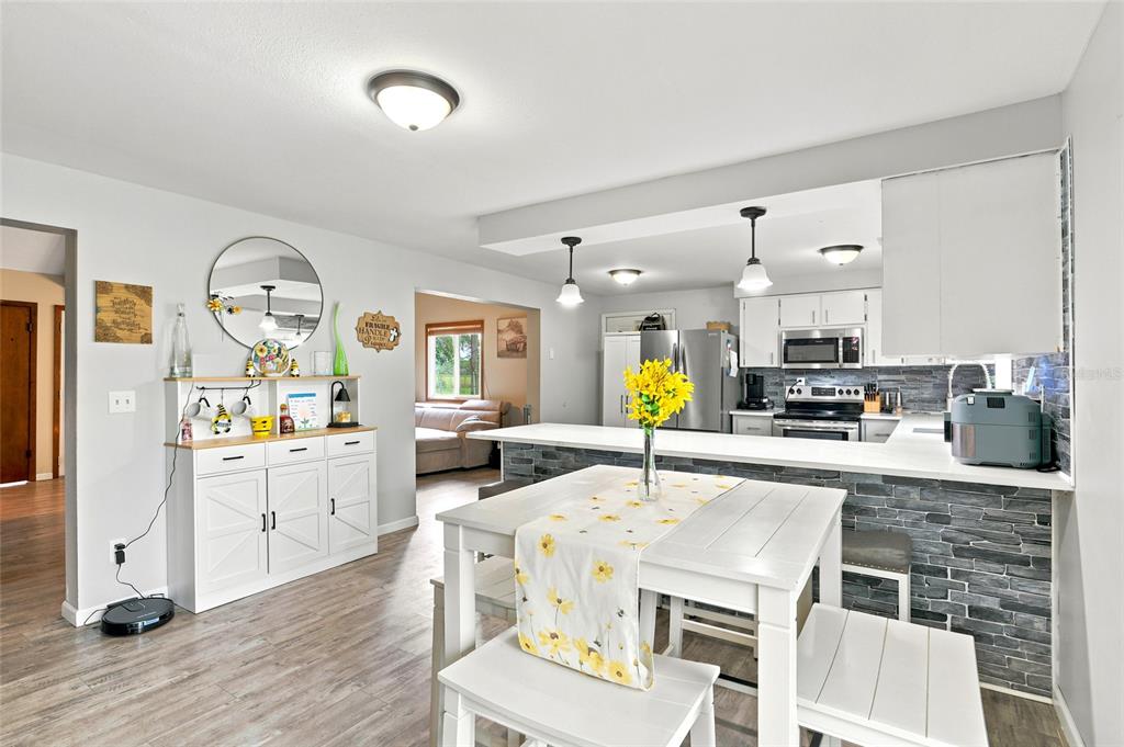 A kitchen and dining area features white cabinetry, a stone backsplash, and a white table — 1518 DICKENS ROAD, LAKE WALES, FL