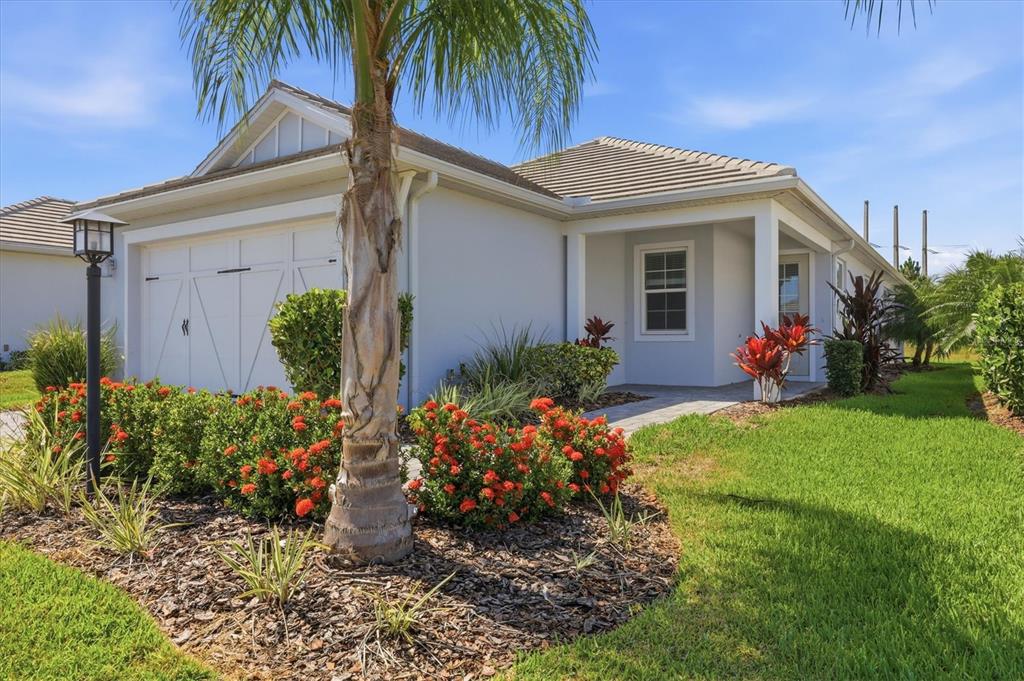 A single-story house with a white garage, a palm tree, and red flowering bushes — 8113 STERNWAY ROAD, SARASOTA, FL