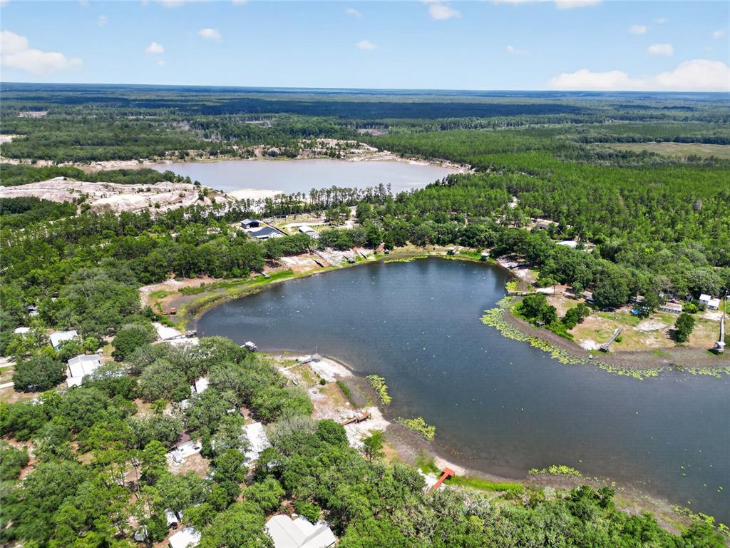 An aerial view shows a lake surrounded by trees, houses, and a sandy area — 273 NEAL ROAD, HAWTHORNE, FL