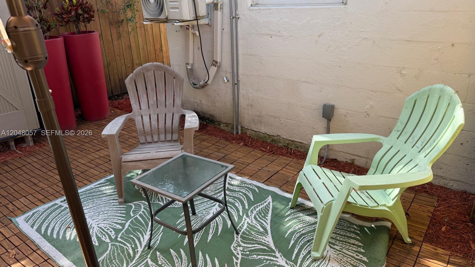 A patio features two Adirondack chairs, a small glass table, and a green rug — 3422 SW 25th St, Miami FL 33133, MIAMI, FL