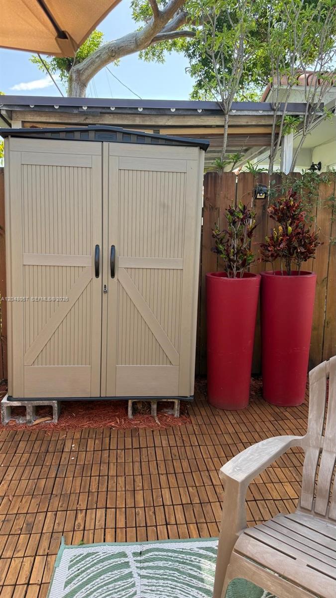 A beige storage shed stands on concrete blocks on a wooden deck near two planters — 3422 SW 25th St, Miami FL 33133, MIAMI, FL
