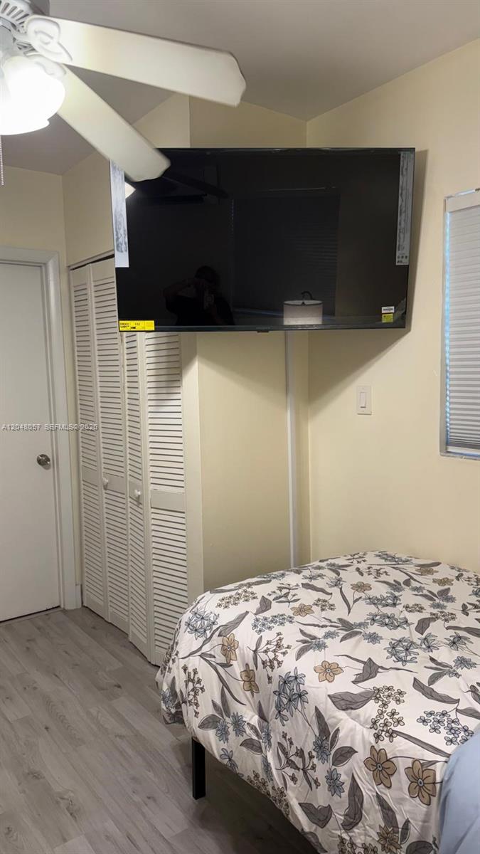 A bedroom features a floral bedspread, a wall-mounted television, and white louvered closet doors — 3422 SW 25th St, Miami FL 33133, MIAMI, FL
