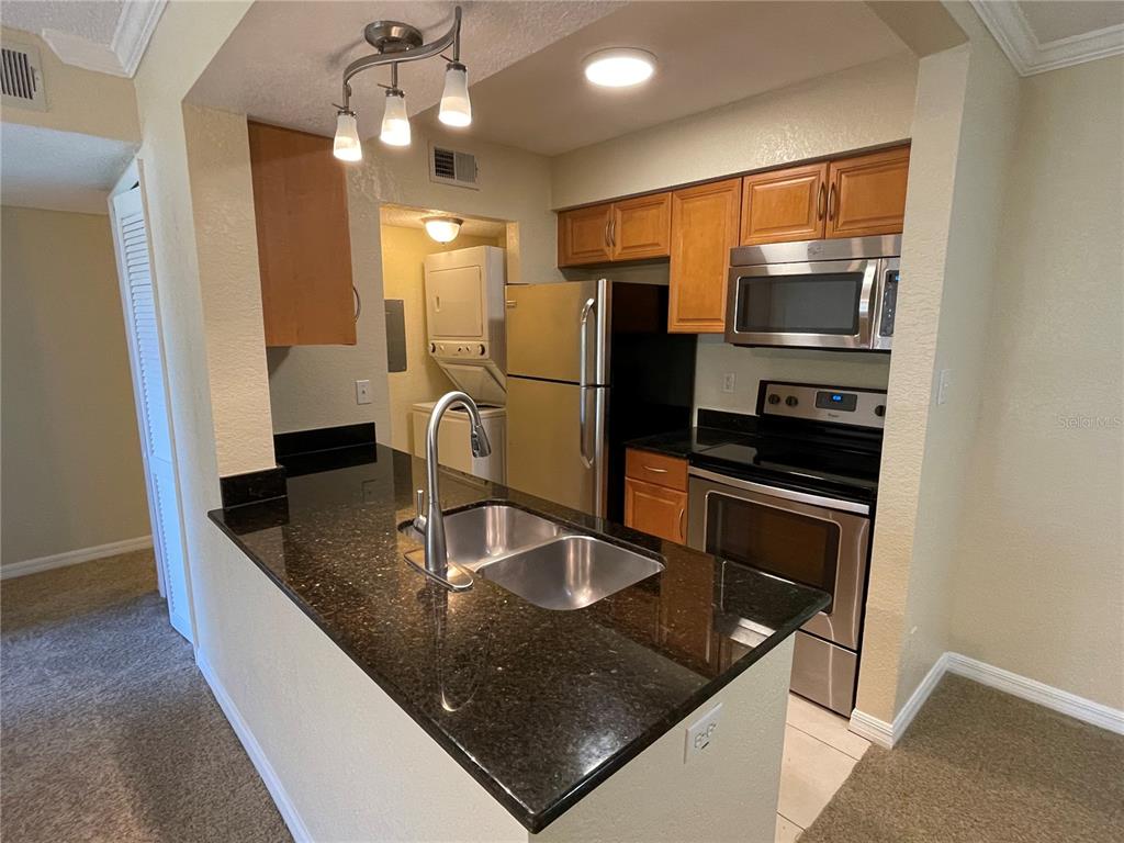 A kitchen features dark granite countertops, stainless steel appliances, and wood cabinetry — 500 BELCHER ROAD S UNIT 18, LARGO, FL