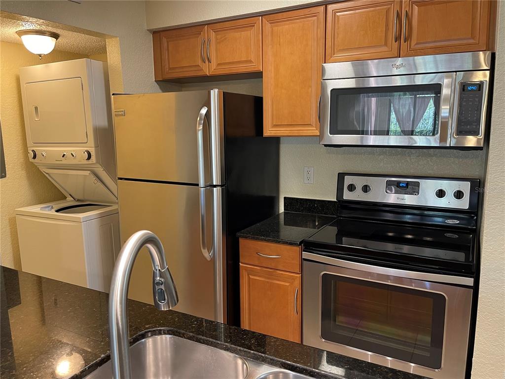 A kitchen features stainless steel appliances, wood cabinets, and dark granite countertops — 500 BELCHER ROAD S UNIT 18, LARGO, FL
