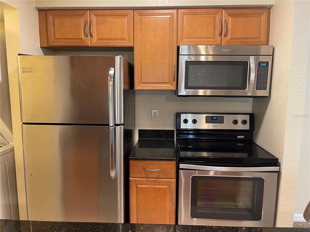 A kitchen features stainless steel appliances, wood cabinets, and black granite countertops — 500 BELCHER ROAD S UNIT 18, LARGO, FL