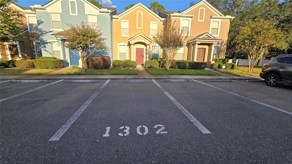A parking space marked 1302 sits in front of a row of multi-story townhomes — 1302 DENMAN COURT, WESLEY CHAPEL, FL