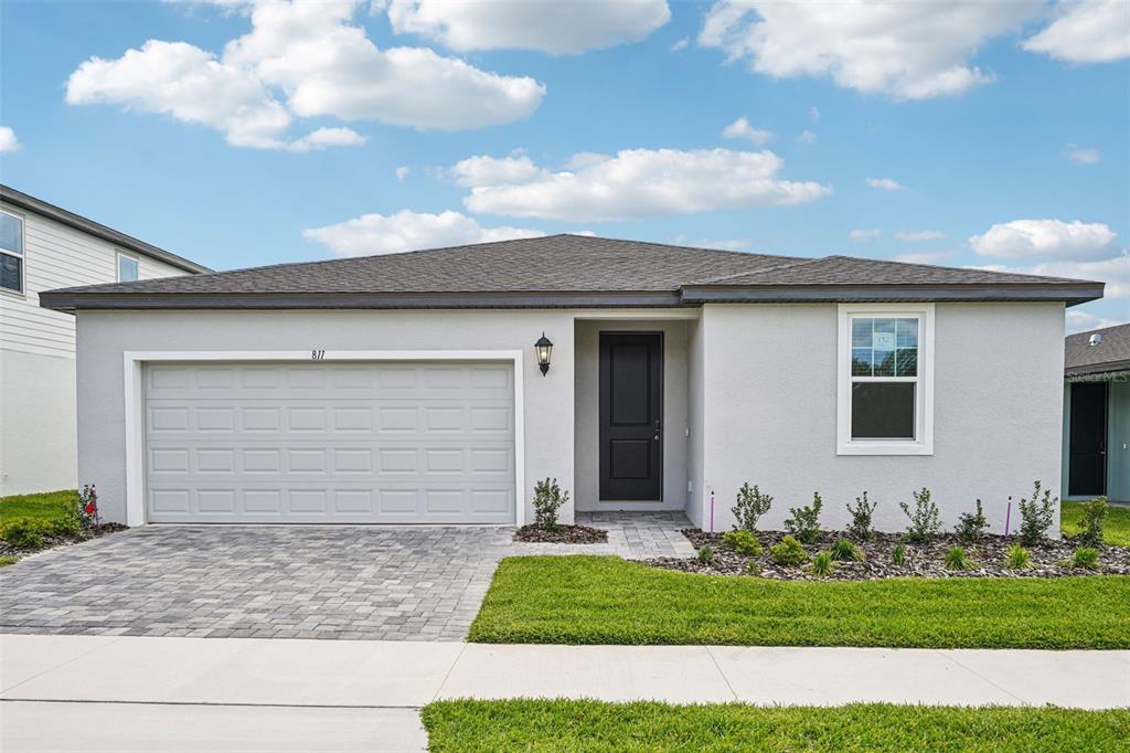 A single-story house with a gray stucco exterior, a two-car garage, and a paved driveway — 811 SUNSHOWER DRIVE, LADY LAKE, FL
