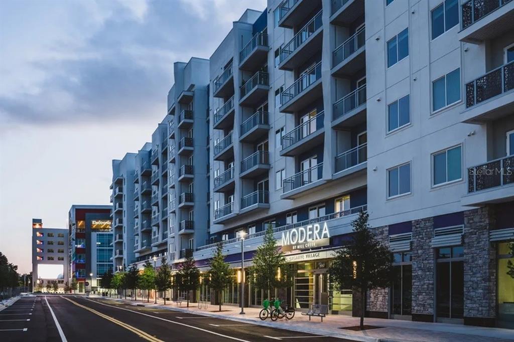 A multi-story apartment building with balconies and ground-floor retail space lines a paved street — 505-1 CHATHAM AVE AVENUE, ORLANDO, FL